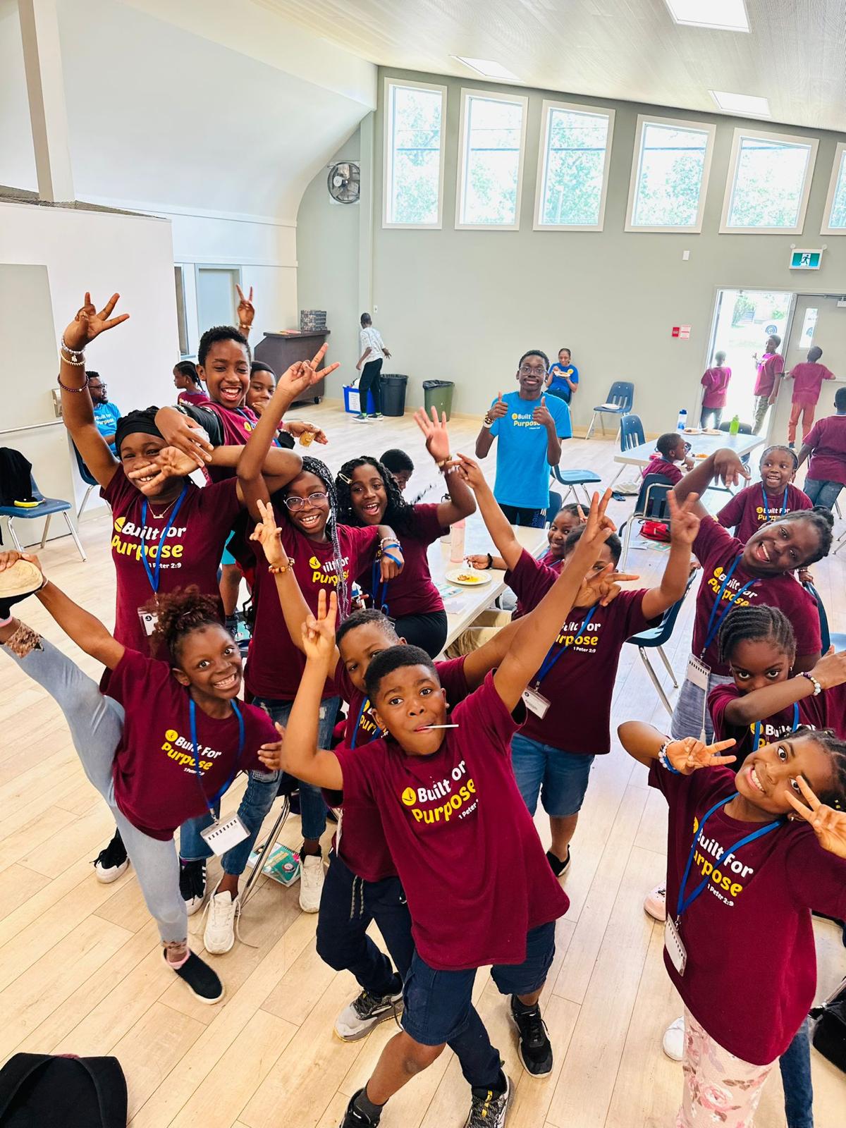 Children at PCG Summer Camp wearing matching camp T-shirts and celebrating together